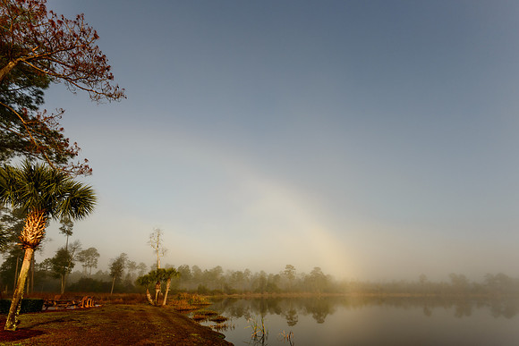 Mist over small lake with fading rainbow over water