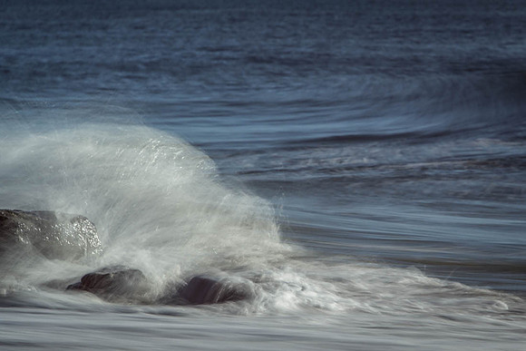 slow motion of morning surf falling over coral rocks on beach