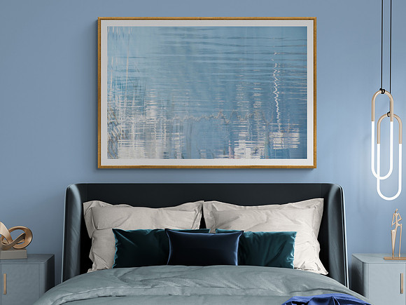 Framed peaceful blue shimmering water image on wall above bed
